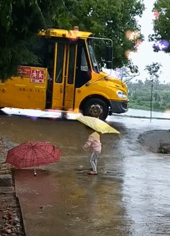 下雨天,3岁妹妹在路边撑著伞接哥哥放学,哥哥下校车时